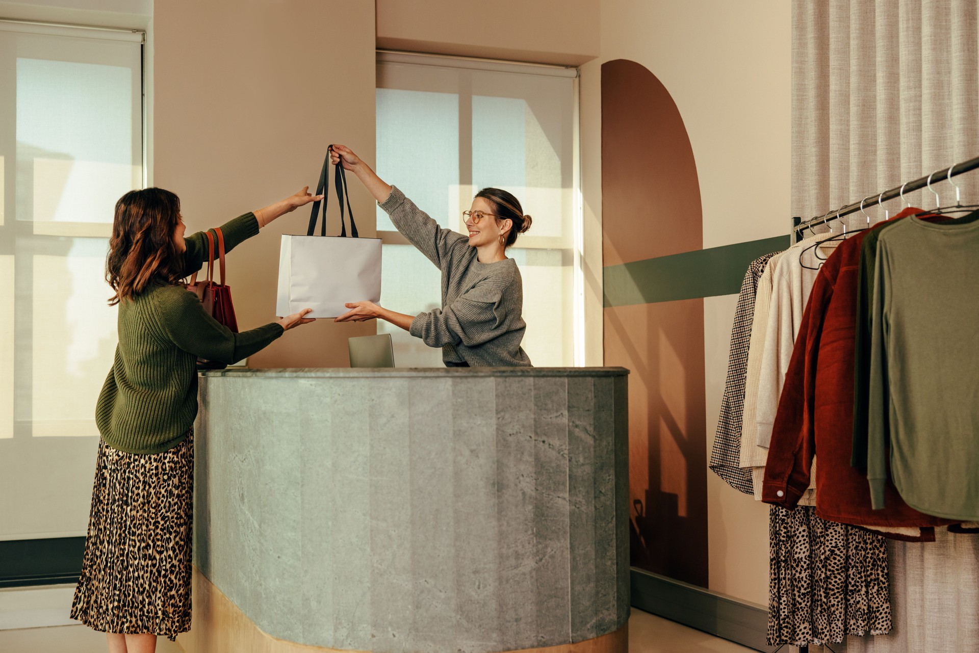 Cheerful clothing store owner assisting a female customer